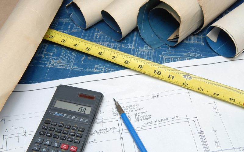 Photo of calculator, measuring table and blue prints for new construction plumbing